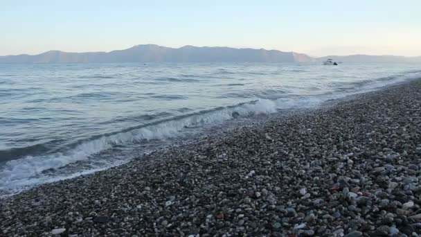 La salida del sol, la mañana sobre el mar con las ondas espumosas contra los guijarros en la playa, la costa — Vídeo de stock