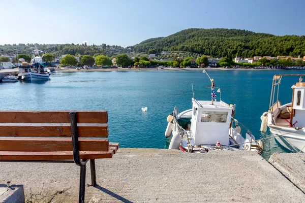 Empty wooden bench at boat dock with beautiful docked fishing bo — Stock Photo, Image