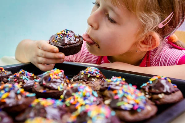 Portret van zoete kindje eten taart, ingericht muffins — Stockfoto