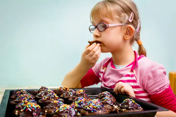 Portret van zoete kindje eten taart, ingericht muffins — Stockfoto