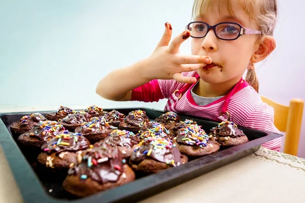 Portret van zoete kindje eten taart, ingericht muffins — Stockfoto