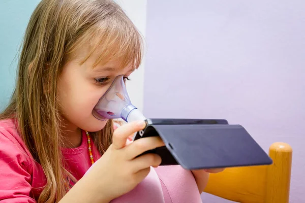 Gadis kecil bermain game di ponsel sampai menggunakan inhaler — Stok Foto