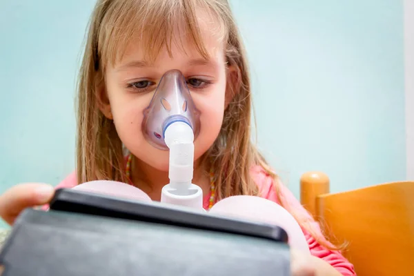 Niña está jugando en el teléfono móvil hasta usar un inhalador — Foto de Stock