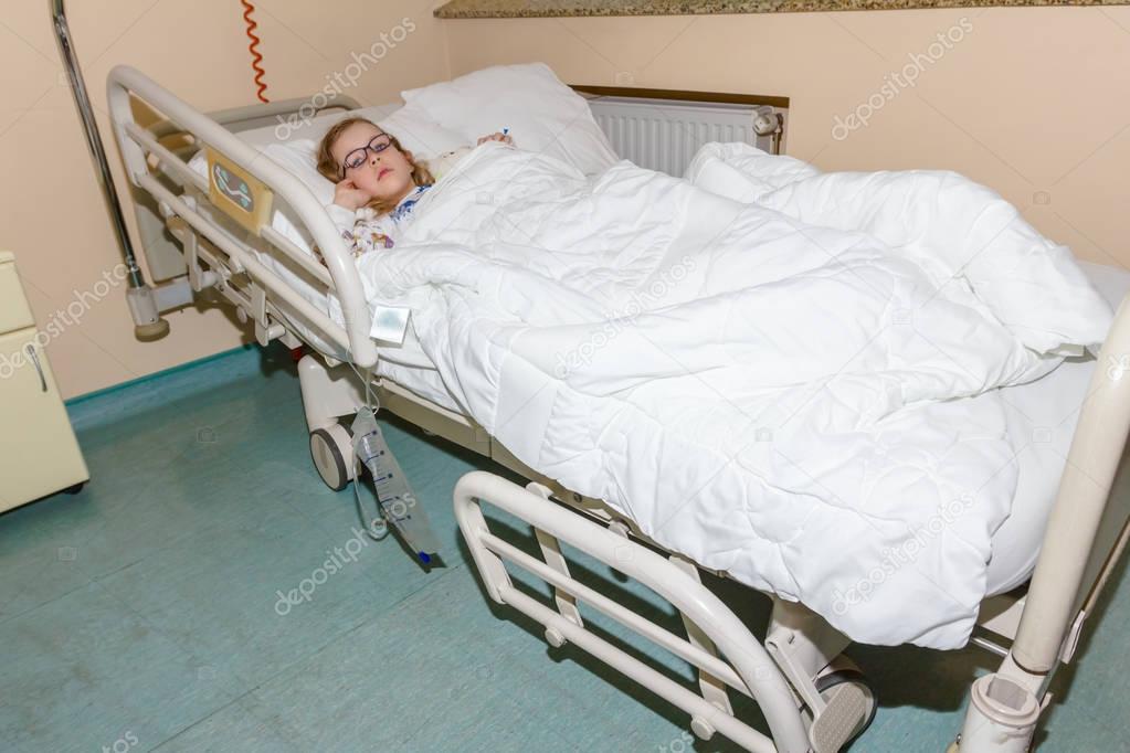 Preschooler child is lying sick on a bed in hospital room	