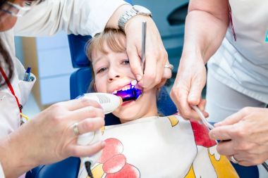 Diş hekimi diş Uv küçük kız açık mout ile tedavi için kullanıyor