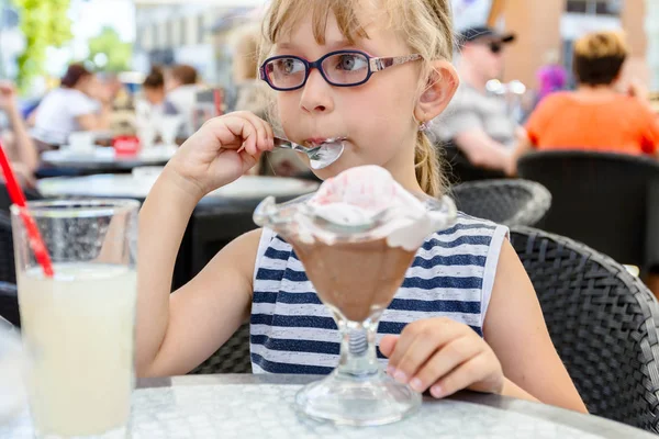 Tatlı küçük kız gözlüklü restoranda dondurma yiyor — Stok fotoğraf