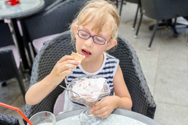 メガネでかわいい女の子がレストランでアイスクリームを食べてください。 — ストック写真