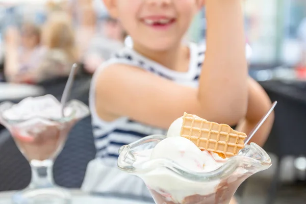 メガネでかわいい女の子がレストランでアイスクリームを食べてください。 — ストック写真