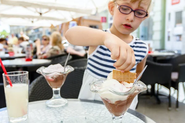 メガネでかわいい女の子がレストランでアイスクリームを食べてください。 — ストック写真