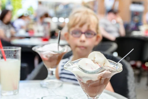 メガネでかわいい女の子がレストランでアイスクリームを食べてください。 — ストック写真