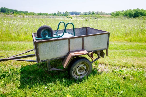 Auto aanhanger met kruiwagen op is geparkeerd op groene landschap — Stockfoto