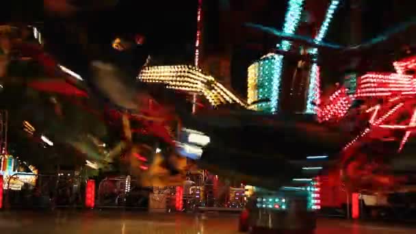 夜ルナ公園の鮮やかな照明に照らされたカラフルなカルーセルを回転 Nightfast で遊園地でカラフルな糸車 — ストック動画