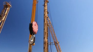 Sitecrane kanca bina üzerinde kırmızı ve beyaz çizgili sinek ile Mobil vinç kanca inşaat site arka planda Tezgahlari, uzun boylu Kuleli üzerinden hareket ediyor.
