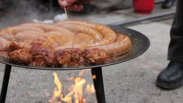库克在烧烤盘上刺穿美味的多汁香肠 用木牙签手在一个黑色烧烤烤肉架上煮香肠小孔 — 图库视频影像