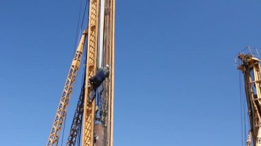 Zrenjanin, Voyvodina, Sırbistan - 23 Nisan 2015:Elder makineleri kule Delme tırmanıyor. İşçi merdivenler üzerinde tırmanıyor ve kule delme, takviye giderir.