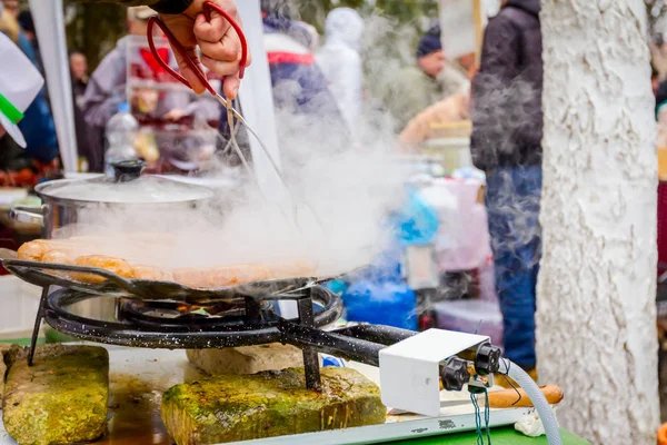 Girando deliziose salsicce succose su piastra barbecue con manico — Foto Stock