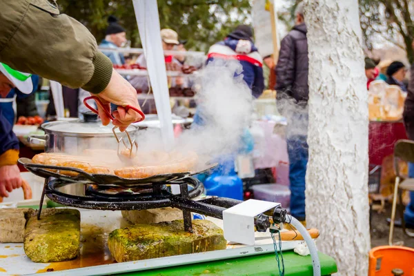 Tourner de délicieuses saucisses juteuses sur plaque de barbecue avec poignée — Photo