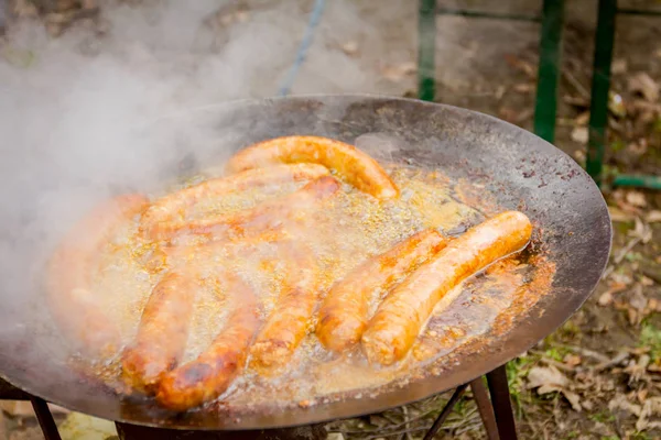 Baking delicious juicy sausages on barbecue plate — Stock Photo, Image