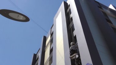 Hızlandırılmış görünümü kadar endüstriyel dağcı'yıkama, cephe temizlik. Genç adam, iş yerinde, endüstriyel dağcı üzerinde yerden görünümünün zaman atlamalı o bina cephe yıkıyor.