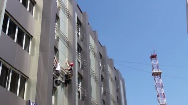 Takım iş yerinde endüstriyel dağcılar onlar bina cephe yıkama vardır. İki endüstriyel dağcılar yıkama, modern ofis binası Cephe Temizlik