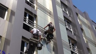 Takım iş yerinde endüstriyel dağcılar onlar bina cephe yıkama vardır. İki endüstriyel dağcılar yıkama, modern ofis binası Cephe Temizlik