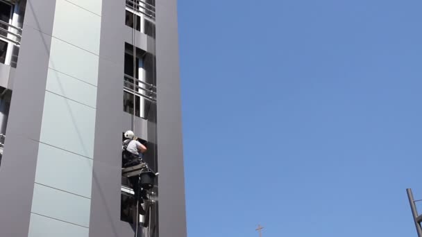 工業用の昇降機は洗濯 若い男が 建物の窓を洗う彼仕事で工業用の昇降機の下から現代のオフィス Buildingview のウィンドウをクリーニング — ストック動画