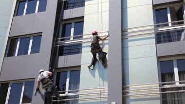 Takım iş yerinde endüstriyel dağcılar onlar bina cephe yıkama vardır. İki endüstriyel dağcılar yıkama, modern ofis binası Cephe Temizlik