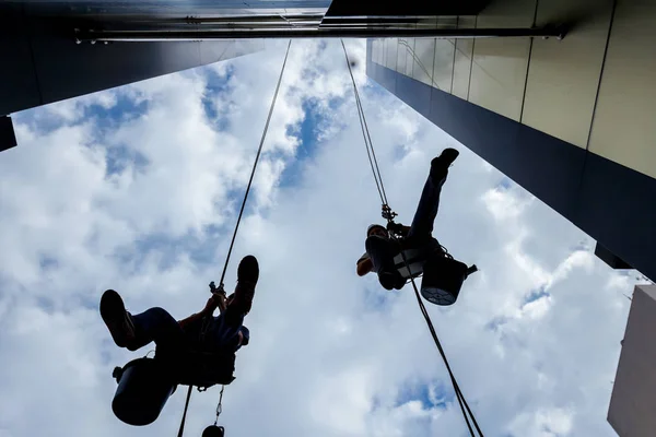 Silhuetas de alpinistas industriais no trabalho, eles estão pulando — Fotografia de Stock