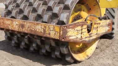 Büyük yol silindiri dikenli toprak inşaat sahasında sıkıştırma. İnşaat işçisi büyük yol silindiri dikenli sürüş ve büyük bir vakıf için toprak sıkıştırma.