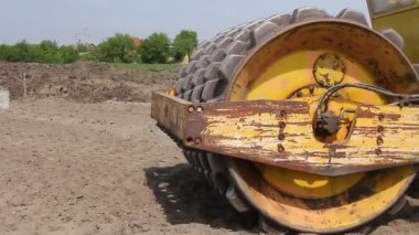 Büyük yol silindiri dikenli toprak inşaat sahasında sıkıştırma. İnşaat işçisi büyük yol silindiri dikenli sürüş ve büyük bir vakıf için toprak sıkıştırma.