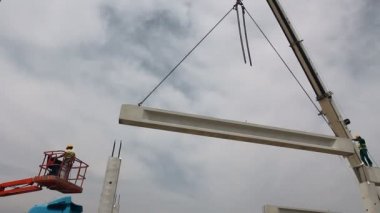 Beton kafes Vinç 's zinciri üzerinde asılı duruyor. Mobil vinç ve yükseklik işçi iskelet yapı üzerinde beton kiriş yerleştirerek.