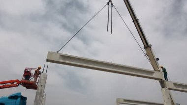 Beton kafes Vinç 's zinciri üzerinde asılı duruyor. Mobil vinç ve yükseklik işçi iskelet yapı üzerinde beton kiriş yerleştirerek.