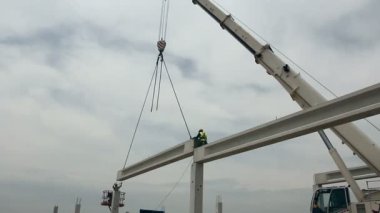 Beton kafes Vinç 's zinciri üzerinde asılı duruyor. Mobil vinç ve yükseklik işçi iskelet yapı üzerinde beton kiriş yerleştirerek.