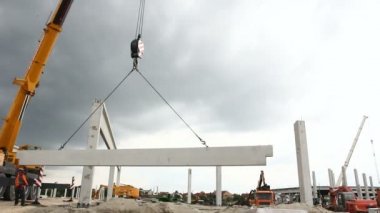 İşçiler vinç yere yardımcı oluyor. İşçiler için derleme büyük inşaat beton kiriş yönetmek için Mobil vinç yardımcı oluyor.