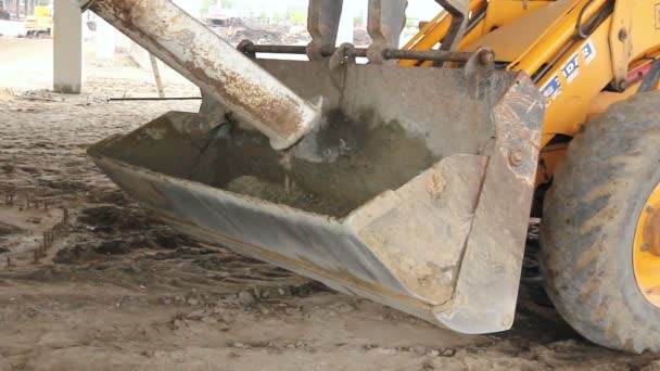 卡车搅拌机正在浇混凝土到推土机铲 醒酒新混凝土在挖掘机前斗中的施工现场运输 — 图库视频影像