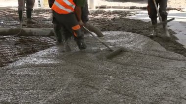 İşçiler beton takviyeli katta büyük inşaat alanı üzerinden yayılıyor. İnşaat İşçileri temel, yapı içinde beton pompa tüp belgili tanımlık doğru yön yönetmenlik yağıyor.