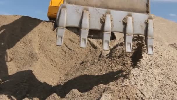 ショベルは サイトの構築にトラック ロードするため砂の山を準備中です 黄色のショベルは建設現場でヒープ 進行中のプロジェクトで地面を引き上げることにより土の山を作っています — ストック動画