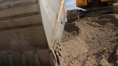 Ekskavatör kum yığını site bina üzerinde kamyon yükleme için hazırlanıyor. Sarı Ekskavatör çekerek yere yığın inşaat sahasında, projesi devam ediyor toprak yığını yapıyor.