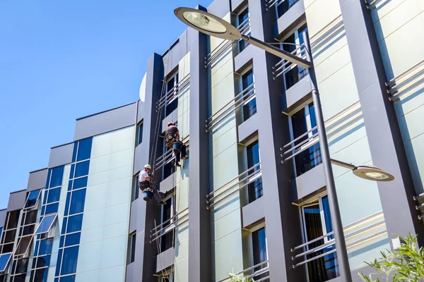 Equipo de escaladores industriales en el trabajo, están lavando la fachada del edificio — Foto de Stock