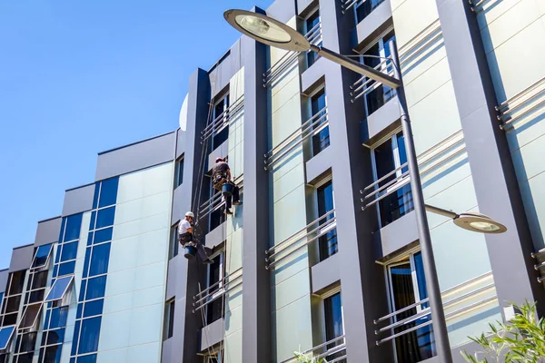 Equipe de alpinistas industriais no trabalho, eles estão lavando fachada edifício — Fotografia de Stock