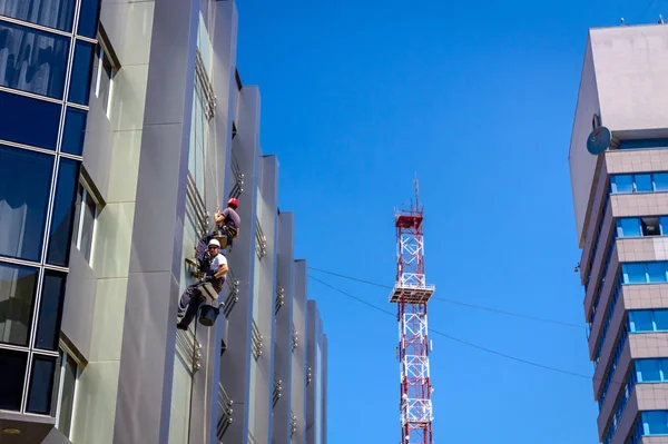 Equipo de escaladores industriales en el trabajo, están lavando la fachada del edificio —  Fotos de Stock