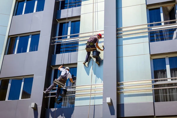 Команда промышленных альпинистов за работой, они моют фасад здания — стоковое фото