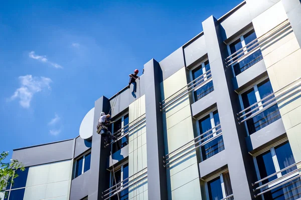 Equipo de escaladores industriales en el trabajo, están lavando la fachada del edificio —  Fotos de Stock