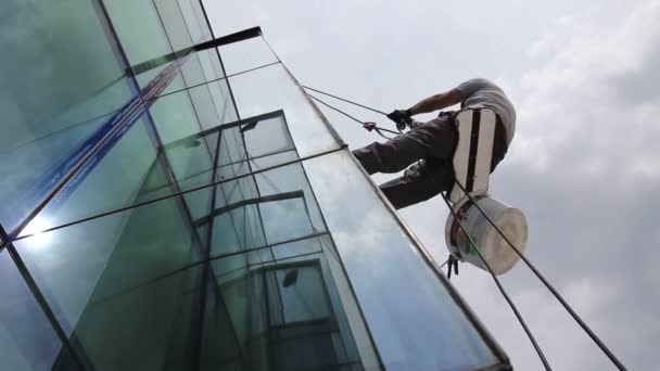 工业登山者在工作 清洁门面的现代化办公大楼 工业登山者正在清洗 清洁门面的现代化办公楼 背景多云的天空 — 图库视频影像