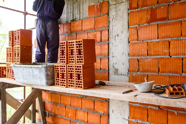 Worker is building wall with red blocks and mortar — Stock Photo, Image