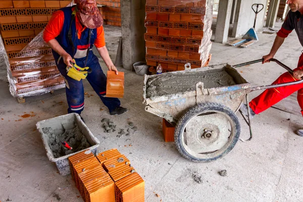 Two workers are pushing industrial tipping wheelbarrow — Stock Photo, Image