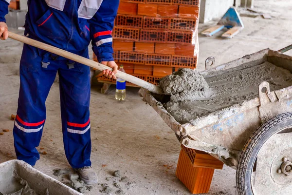 Dělník používá lopatu k vykládce kolečka na staveništi — Stock fotografie