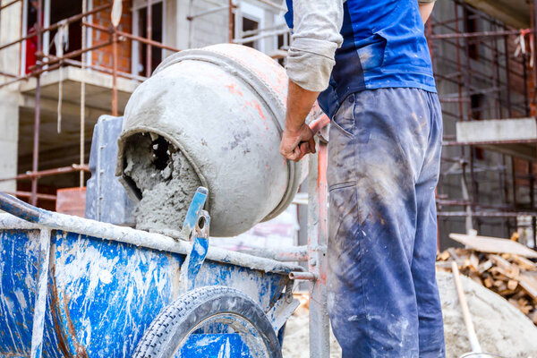 Worker is pour mortar in wheelbarrow 