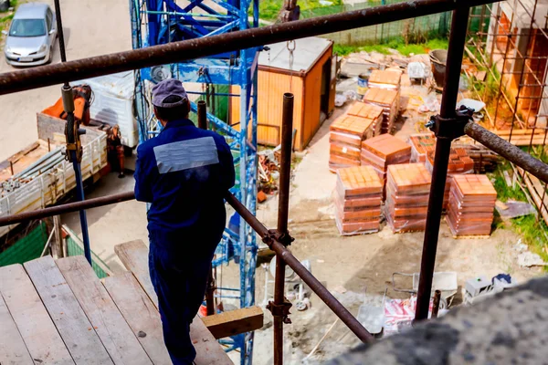 Arbetaren tittar på byggarbetsplatsen ovanifrån, stående på Sca — Stockfoto