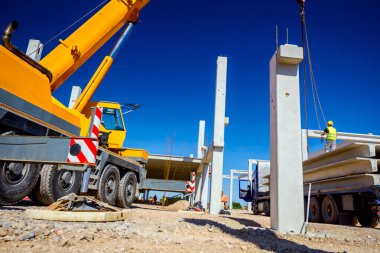 İşçi kamyon yolundaki beton kirişe vinç kancaları takıyor.